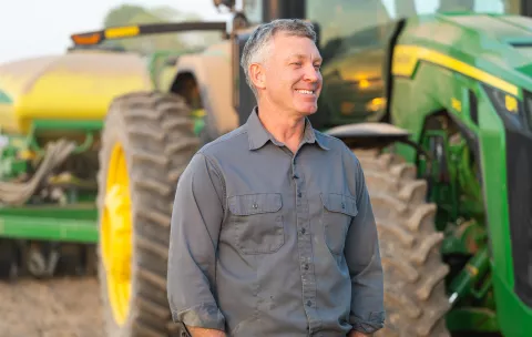 Jeff Rowe stands in front of his tractor smiling